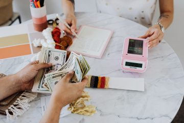 Duas pessoas sentadas ao redor de uma mesa, contando dinheiro e somando contas